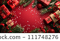 Festive Christmas composition with red gifts, pine branches, and holiday ornaments on a red background with snowflakes. 111748276