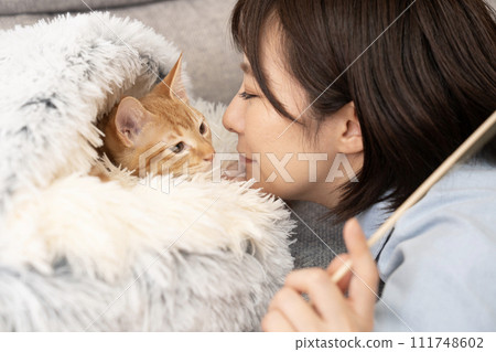 一個女人把臉靠近床上的一隻小貓 111748602