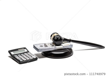 A legal gavel atop American currency with a calculator, depicting financial law or fines. A legal gavel atop American currency with a calculator, depicting financial law or fines. 111748979