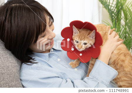 A smiling woman with a kitten with a red Elizabethan collar 111748991