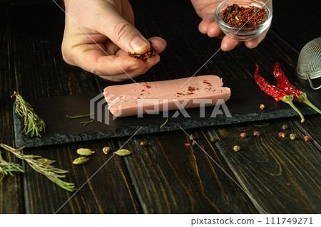 Cooking Munich milk sausage on the kitchen table. The chef hands add aromatic spices to the sausage on the kitchen table before baking in the oven. Serving diet food for breakfast. 111749271