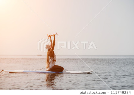 Woman sea sup. Close up portrait of happy young caucasian woman with long hair looking at camera and smiling. Cute woman portrait in bikini posing on sup board in the sea Woman sea sup. Close up portrait of happy young caucasian woman with long hair looking at camera and smiling. Cute woman portrait in bikini posing on sup board in the sea 111749284