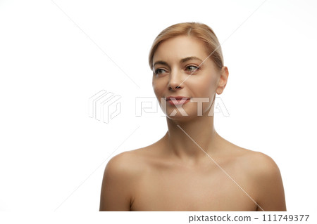 Portrait of smiling blonde beautiful woman with bare shoulders looking away against white studio background. 111749377