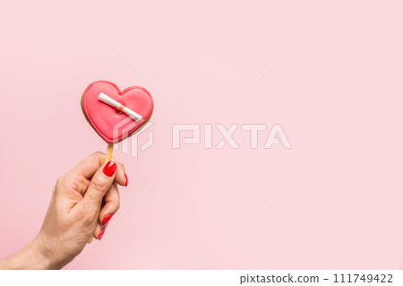Valentine's Day red glazed cookies in shape of heart in woman hand on pink background. Banner. Greeting card copy space. Valentine's Day red glazed cookies in shape of heart in woman hand on pink background. Banner. Greeting card copy space. 111749422