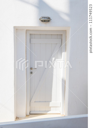 Front view of white wooden door in a white wall Front view of white wooden door in a white wall 111749523