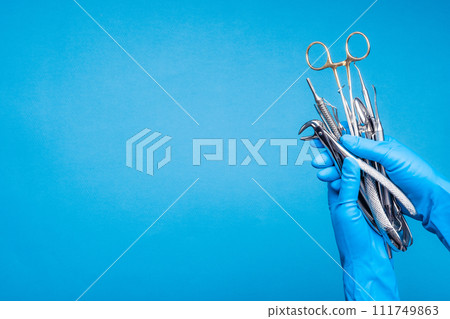 Hand in blue glove holding surgery dental tools Hand in blue glove holding surgery dental tools 111749863