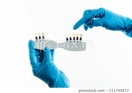 Hands in blue gloves holding dental color palette isolated Hands in blue gloves holding dental color palette isolated 111749877