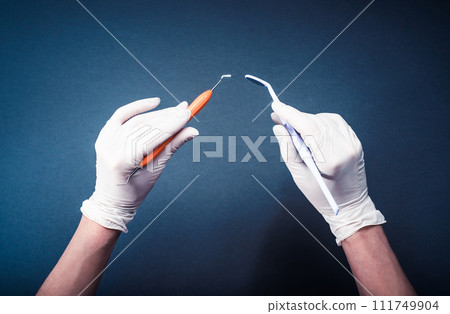 Hands in white gloves holding dental tools Hands in white gloves holding dental tools 111749904