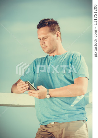 Man tourist on pier using smartphone. Technology. Man tourist on pier using smartphone. Technology. 111751200