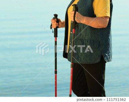 active woman senior nordic walking on a beach 111751362