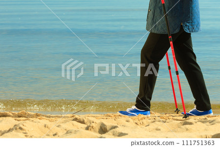 active woman senior nordic walking on a beach. legs 111751363