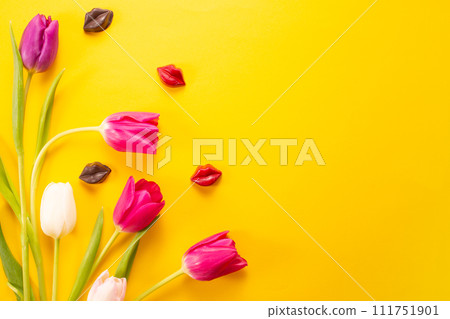 Yellow tulips and chocolate lips on a yellow background, top view, international woman's day, spring bouquet Yellow tulips and chocolate lips on a yellow background, top view, international woman's day, spring bouquet 111751901