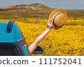 Summer road trip concept. Hat holding a straw hat from opened car window 111752041