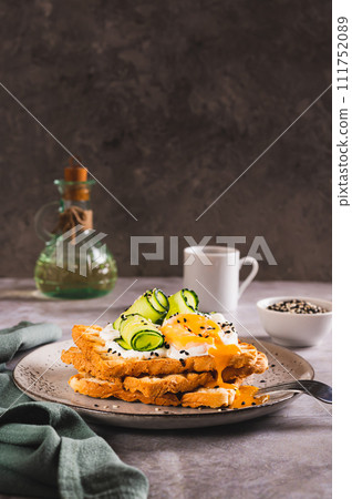 Toasts with cream cheese, cucumber, poached egg and sesame seeds on a plate vertical view 111752089