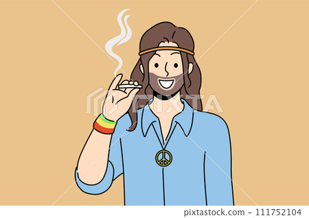 Hippie man smoking cannabis and smiles, standing with symbol of pacifist subculture on chest 111752104