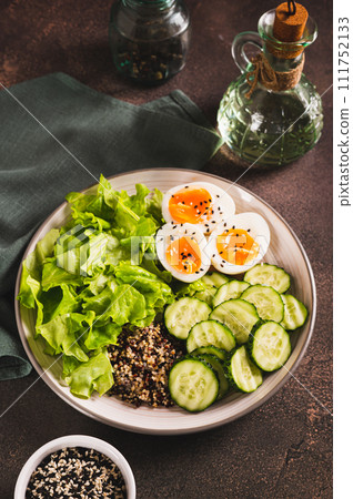 Fitness plate with quinoa, cucumber, egg and lettuce on the table vertical view Fitness plate with quinoa, cucumber, egg and lettuce on the table vertical view 111752133