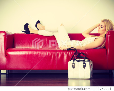 Woman lying on sofa presenting white bag 111752201