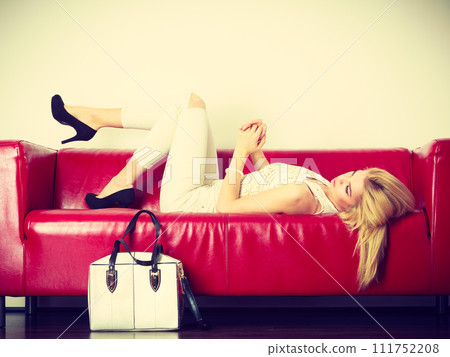 Woman lying on sofa presenting white bag 111752208