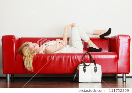 Woman lying on sofa presenting white bag 111752209