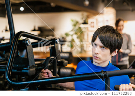 A man receiving guidance from a trainer at a fitness gym A man receiving guidance from a trainer at a fitness gym 111752293