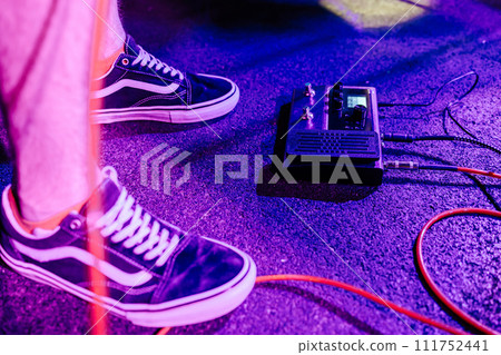 Guitar processor. The guitarist presses the pedal with his foot to change the sound. rock concert in a bar Guitar processor. The guitarist presses the pedal with his foot to change the sound. rock concert in a bar 111752441
