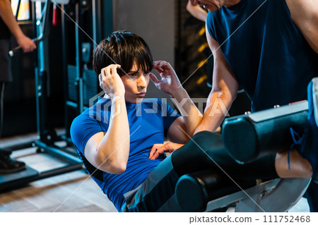 A man receiving guidance from a trainer at a fitness gym 111752468