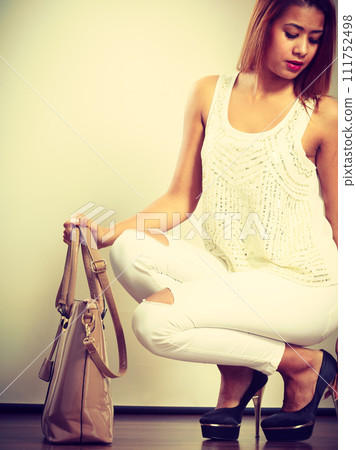 Mulatto woman holding beige leather bag. Mulatto woman holding beige leather bag. 111752498