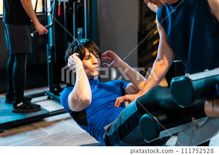 A man receiving guidance from a trainer at a fitness gym A man receiving guidance from a trainer at a fitness gym 111752528