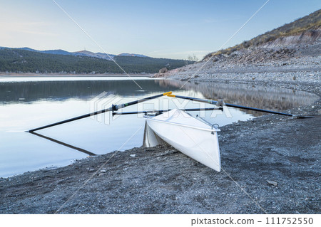Coastal rowing shell on a shore of Carter Lake in northern Colorado at dusk in winter scenery 111752550