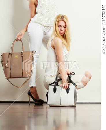 Two women in white clothes with bags handbags. 111752565