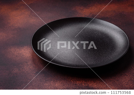 Empty ceramic round plate on dark textured concrete background Empty ceramic round plate on dark textured concrete background 111753568