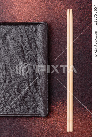 Empty black square ceramic plate on dark concrete background 111753654
