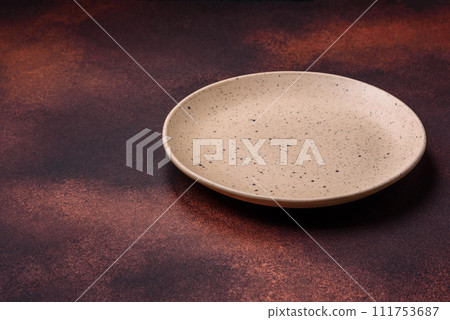 Empty ceramic round plate on dark textured concrete background Empty ceramic round plate on dark textured concrete background 111753687