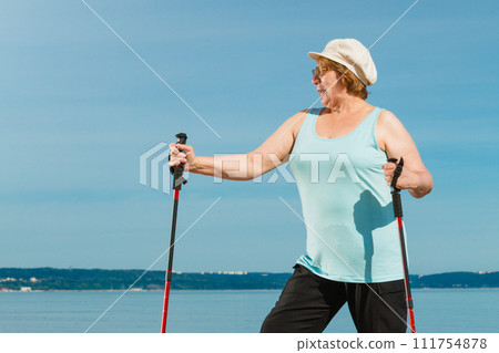 Senior woman practicing nordic walking on beach 111754878