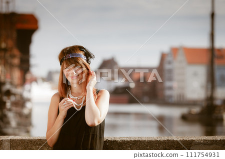 Flapper girl woman in1920s style standing on the street Flapper girl woman in1920s style standing on the street 111754931