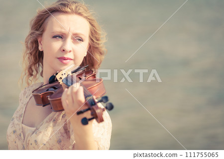 Woman playing violin on violin near beach Woman playing violin on violin near beach 111755065