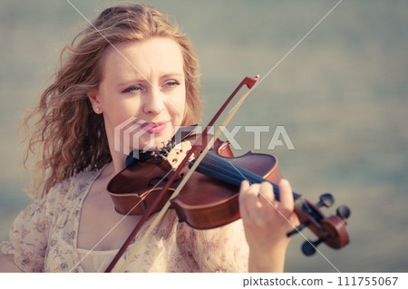 Woman playing violin on violin near beach Woman playing violin on violin near beach 111755067