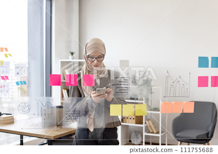 Muslim woman in hijab solving business issues while typing on smartphone. Muslim woman in hijab solving business issues while typing on smartphone. 111755688
