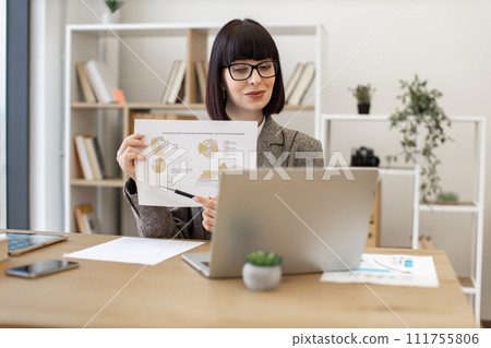 Confident female holding paper with information in front of laptop webcam. 111755806