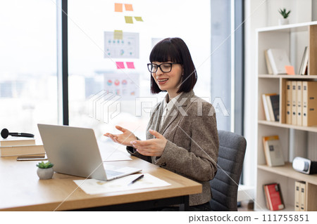 Businesswoman receiving video call on computer while sitting at office desk. 111755851