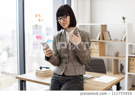 Female in formal outfit recording video on mobile phone while sitting in table. 111755959