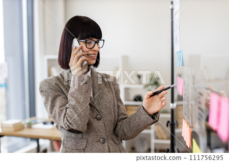 Woman in formal wear and glasses solving business issues having phone call. 111756295