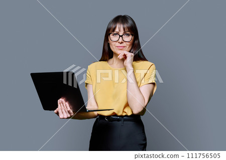 Middle-aged woman using laptop computer on gray studio background 111756505