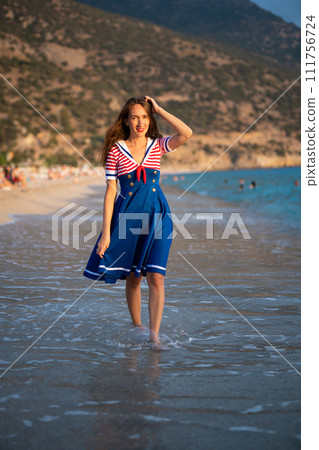 a beautiful sexy girl in a sea uniform walks on the beach 111756724