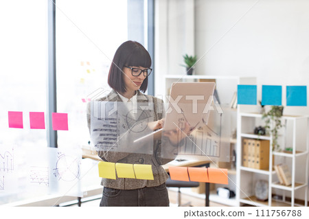 Caucasian woman in formal wear and glasses solving business issues with laptop. 111756788