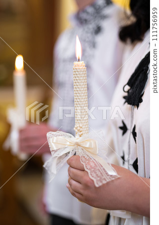 Beautifully burning candle held in hands in the church Beautifully burning candle held in hands in the church 111756959