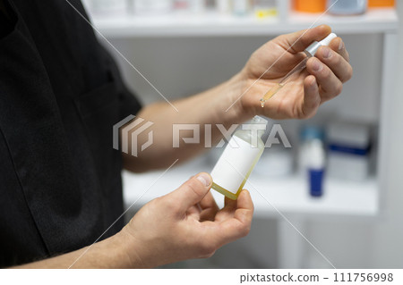 while holding a jar and a pipette, the liquid is poured 111756998