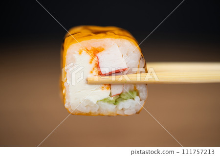 delicious traditional Japanese sushi and rolls on a plate holding chopsticks delicious traditional Japanese sushi and rolls on a plate holding chopsticks 111757213