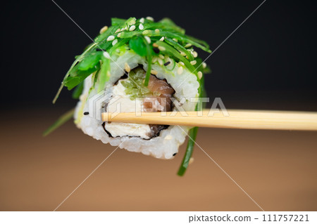 delicious traditional Japanese sushi and rolls on a plate holding chopsticks 111757221
