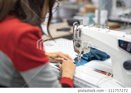 workers in an industrial garment factory sew clothes on sewing machine 111757272